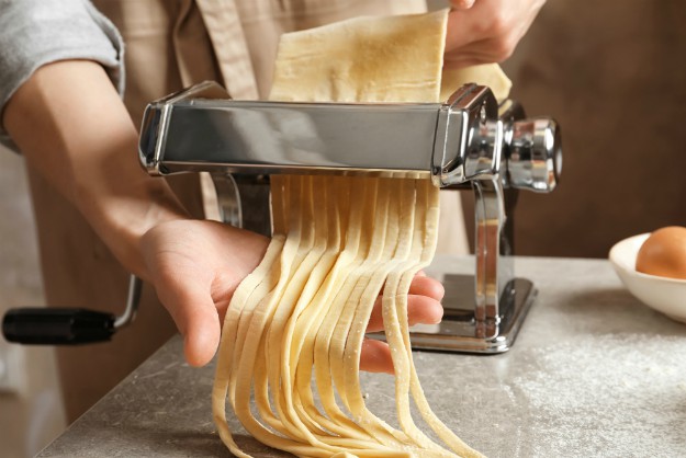 Young woman preparing noodles with pasta maker at table  | Hand-Powered Tools & Appliances | The Power Of Primitive Tools